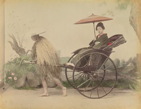 [Woman with Parasol Posed Being Pulled in a Jinrikisha by a Man Wearing a Straw Rain Coat]