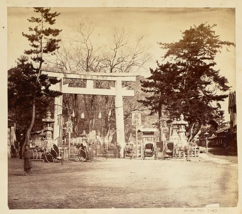 [Torii surrounded by several rickshaws in a village square]