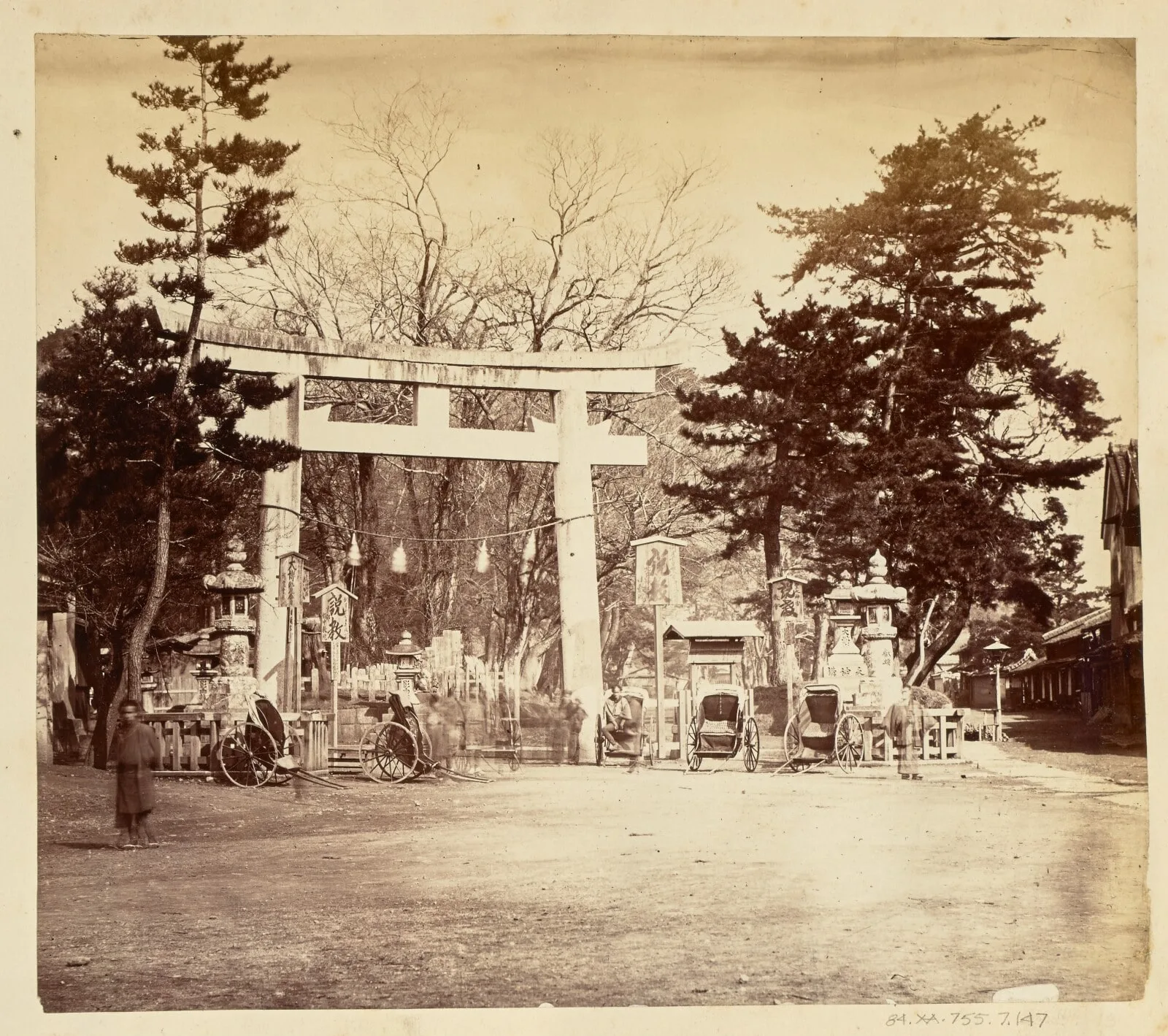 [Torii surrounded by several rickshaws in a village square]